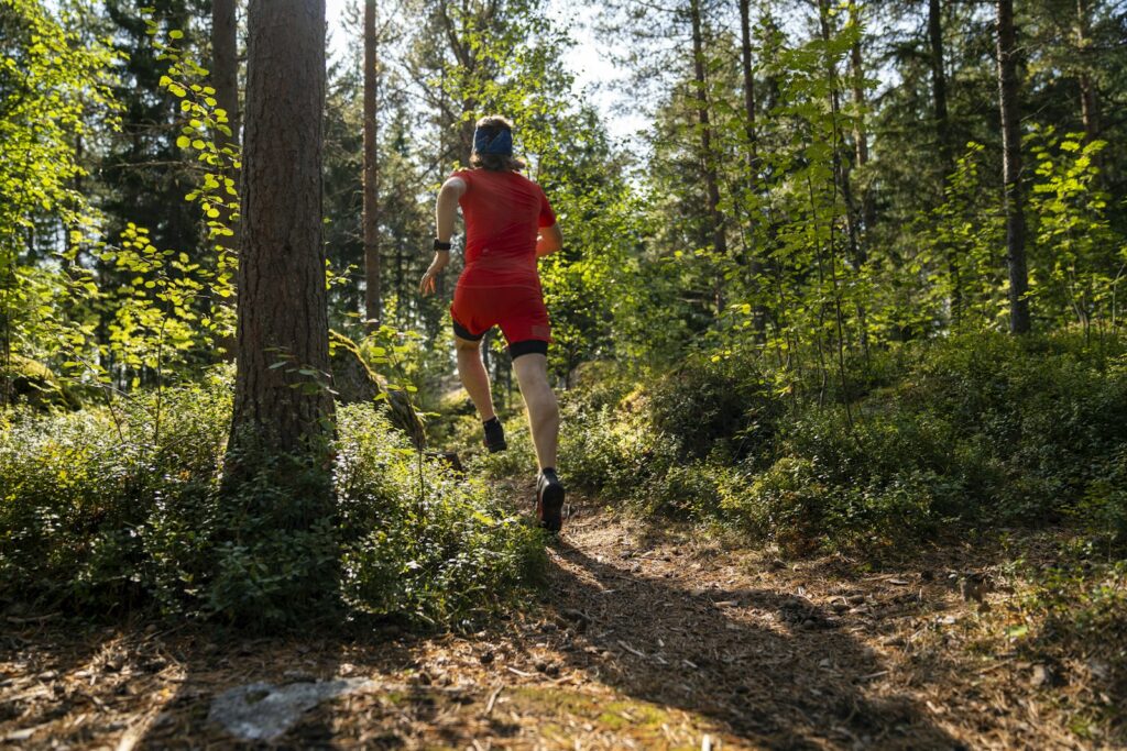 Löpare i röd tröja springer genom skogen